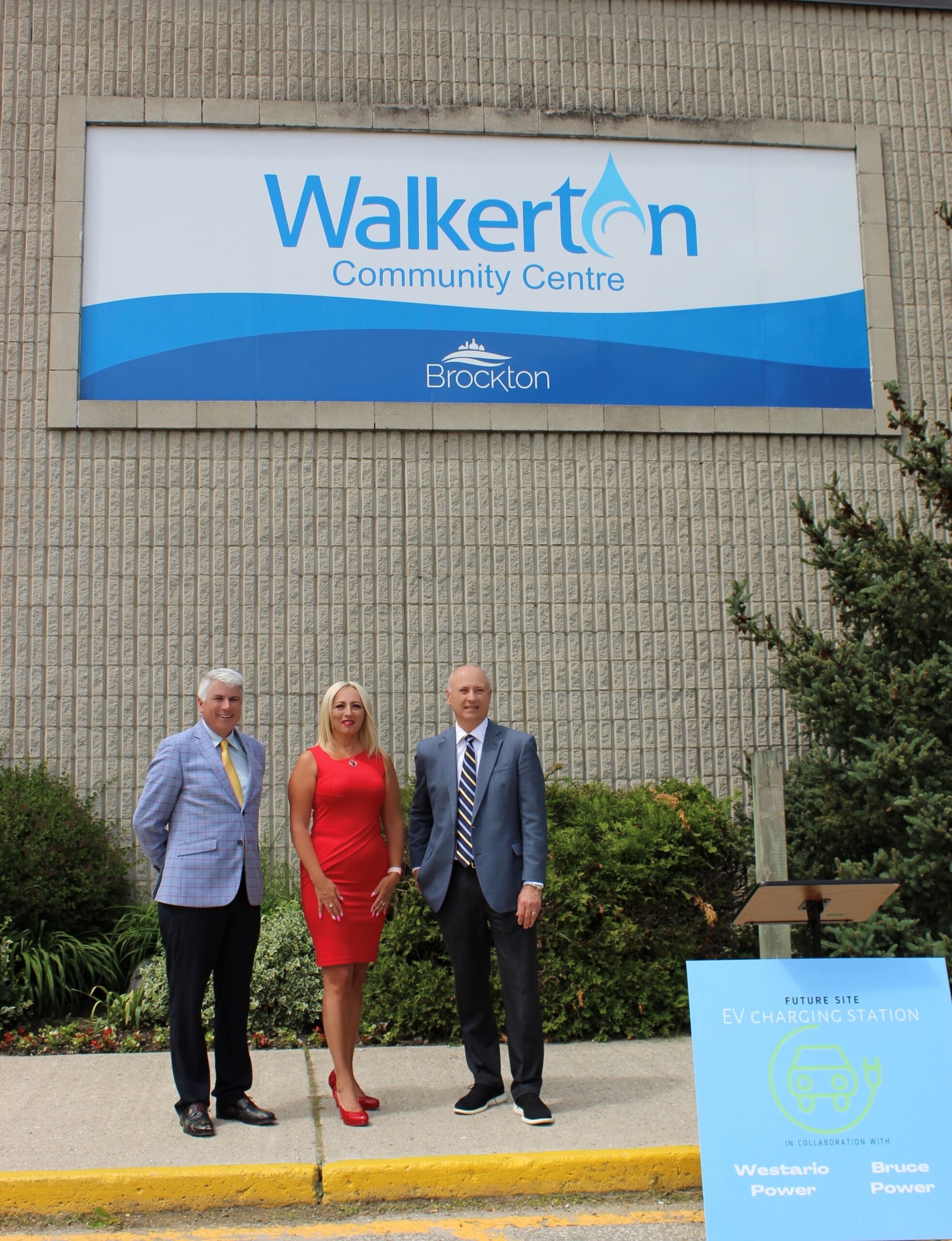 Bruce Power CEO Mike Rencheck, Westario Power CEO Jenny Alfandary, and Brockton Mayor Chris Peabody stand in front of Walkerton sign